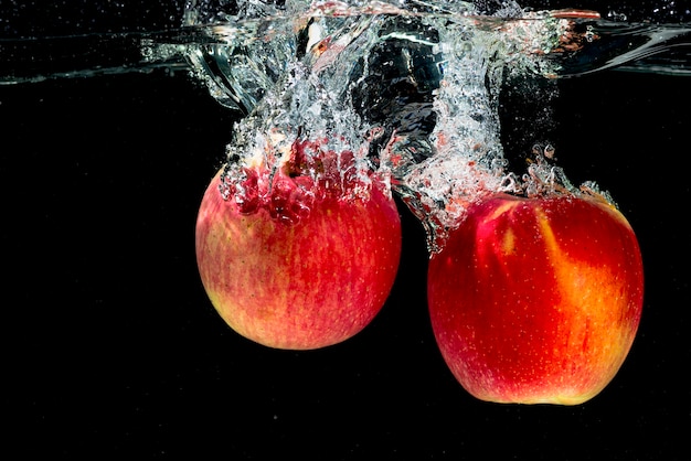 Twee rode appels spetteren in het water