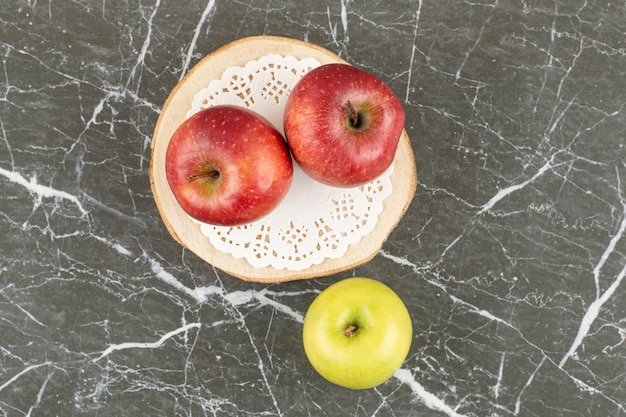 Twee rode en één groene appels. Op houten bord.