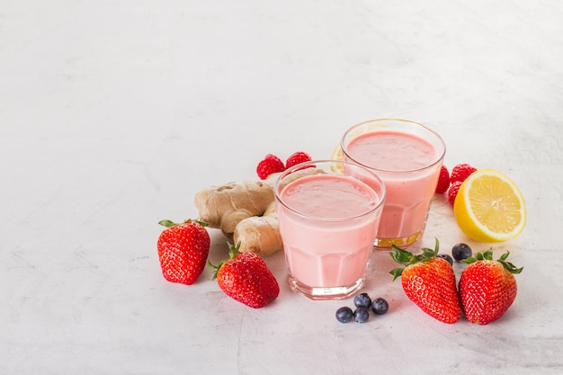 Twee rode smoothies met aardbeien, gember en citroen