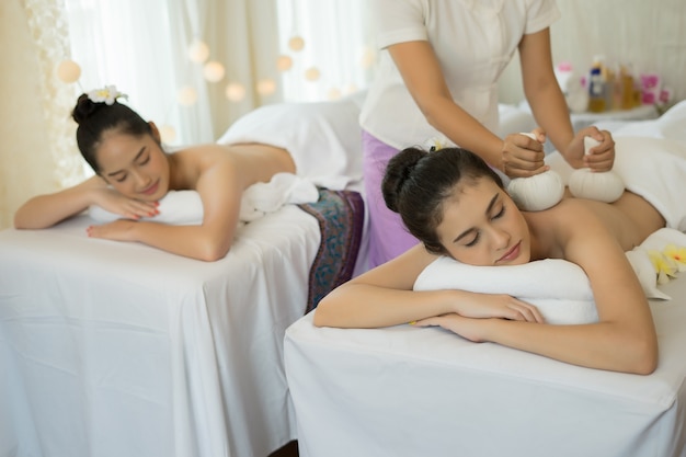 Twee schattige jonge vrouwen genieten van ontspannen tijdens een massage in de spa.