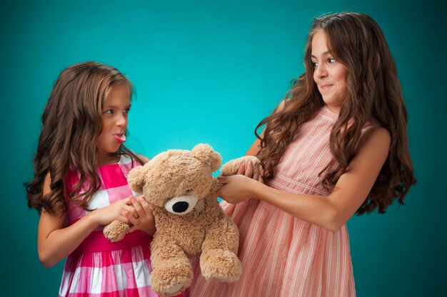 twee schattige kleine meisjes op blauw met teddybeer