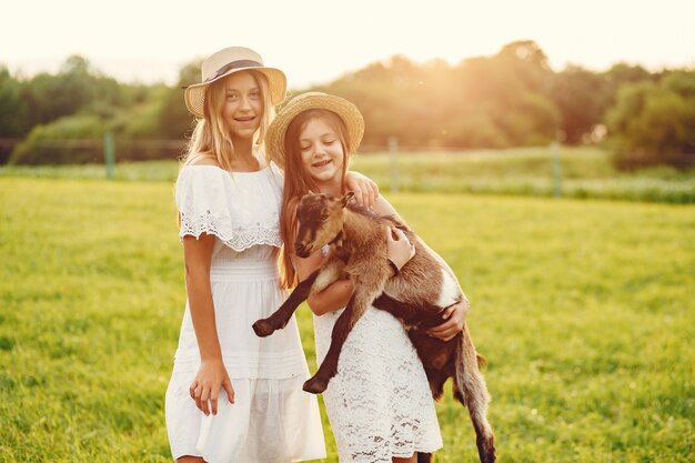 Twee schattige meisjes in een veld met een geit