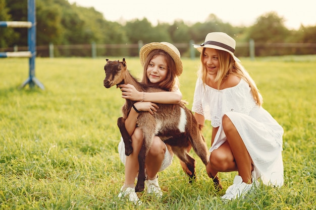 Twee schattige meisjes in een veld met een geit