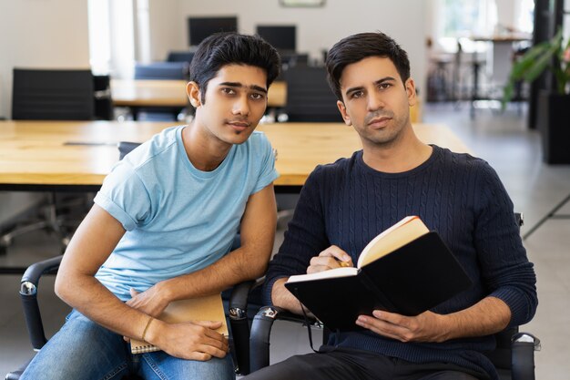 Twee serieuze medestudenten studeren en kijken naar de camera