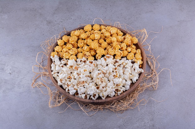 Twee smaken popcorn geserveerd op een houten dienblad versierd met stro op marmeren achtergrond. Hoge kwaliteit foto