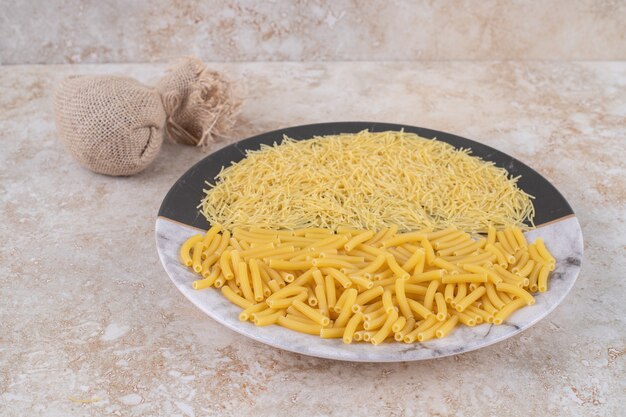 Twee soorten ongekookte macaroni op een mooi bord