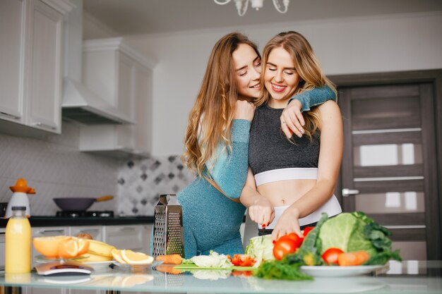 Twee sportenmeisje in een keuken met groenten