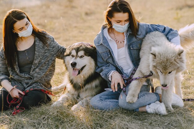 Twee stijlvolle meisjes in een zonnig veld met honden