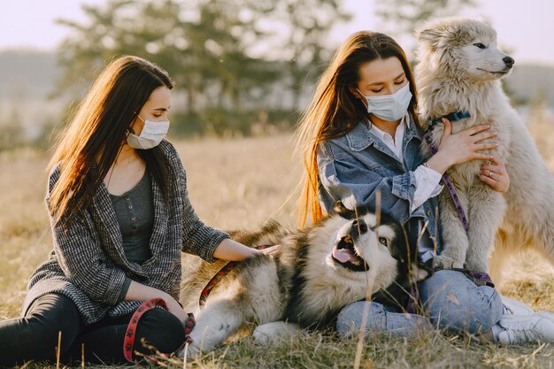 Twee stijlvolle meisjes in een zonnig veld met honden