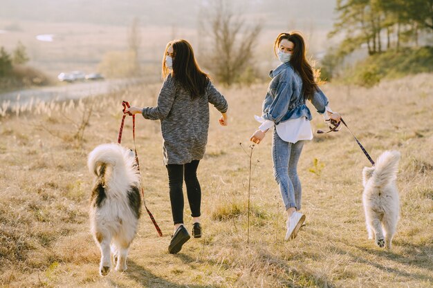 Twee stijlvolle meisjes in een zonnig veld met honden