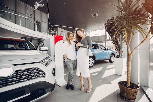 Twee stijlvolle vrouwen in een autosalon