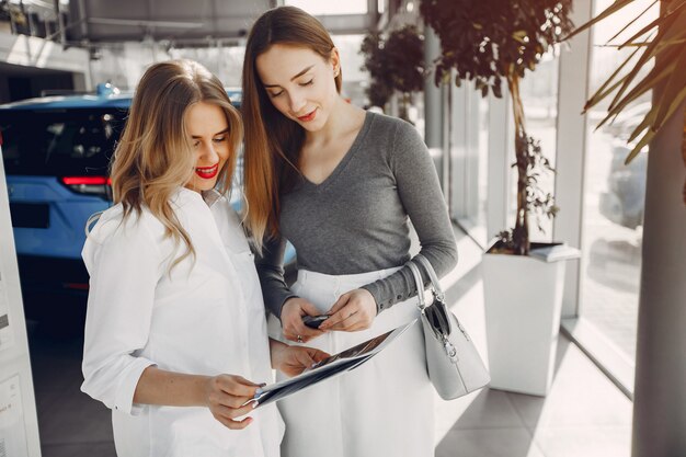 Twee stijlvolle vrouwen in een autosalon