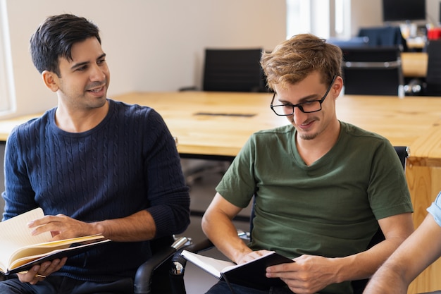 Twee studenten die studeren, samen leerboeken lezen en praten