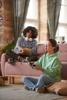 Twee tieners die thuis rusten, videogames spelen en boeken lezen