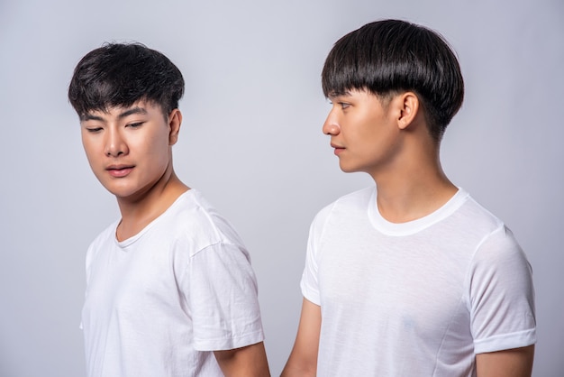 Twee verliefde mannen in witte t-shirts keken elkaars gezichten aan.