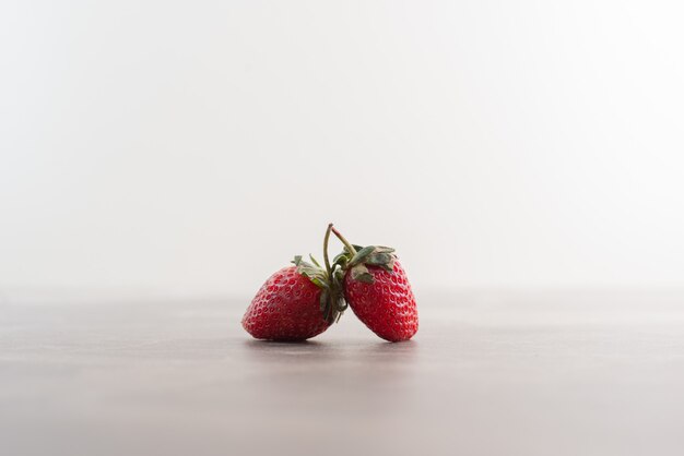 Twee verse aardbeien op marmeren tafel.