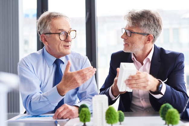 Gratis foto twee volwassen architecten bespreken bedrijfsstrategie