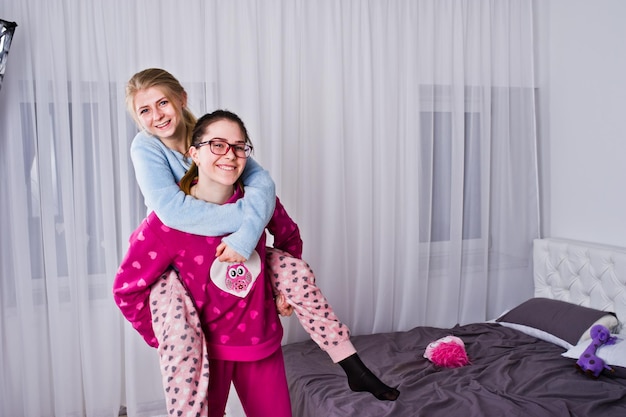 Gratis foto twee vriendenmeisjes in pyjama die plezier hebben op bed in de kamer