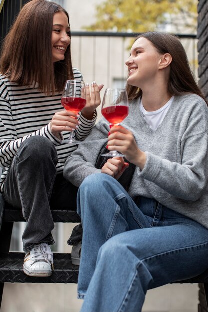 Twee vriendinnen glimlachen en juichen met een glas wijn