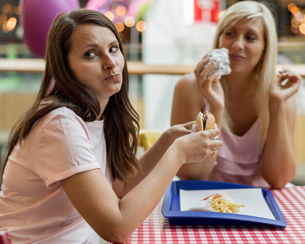 Twee vriendinnen hamburgers eten in restaurant