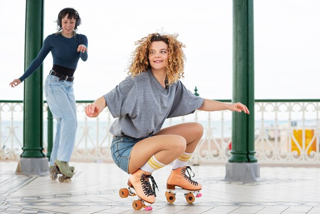 Twee vriendinnen met rolschaatsen die buiten rollen en dansen