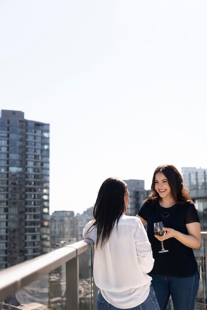 Gratis foto twee vriendinnen op een dakterras wijn drinken en praten