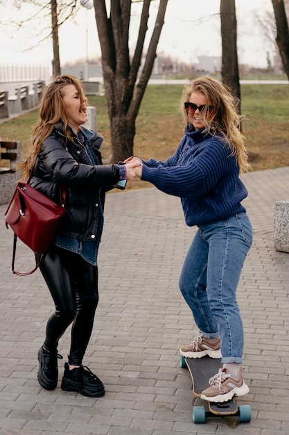 Gratis foto twee vriendinnen plezier buitenshuis skateboarden