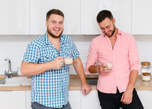 Twee vrolijke jonge mannen met koffie in de keuken