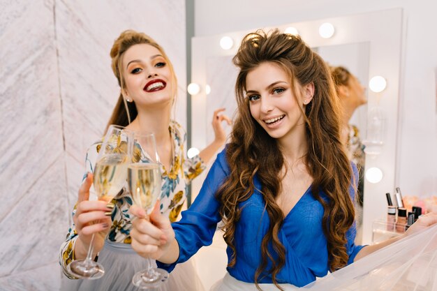 Twee vrolijke jonge vrouwen met een luxe uitstraling die plezier hebben in de kapsalon