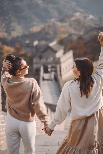 Twee vrouwelijke vrienden die langs de Grote Muur van China dichtbij het gevolg van Peking lopen