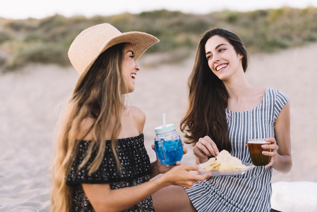 Gratis foto twee vrouwelijke vrienden lachen op het strand
