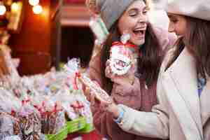 Gratis foto twee vrouwen die gemberbrood op kerstmarkt kopen