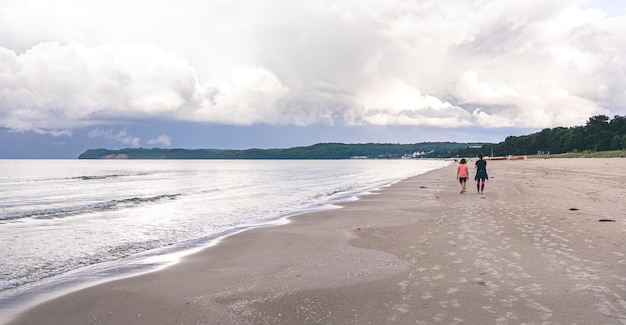 Twee vrouwen lopen langs een leeg zeestrand