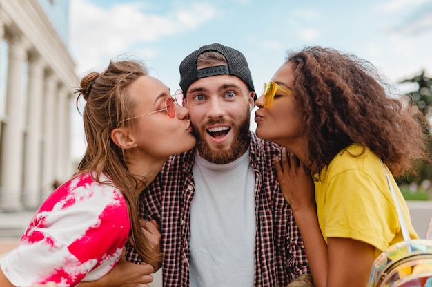 Twee vrouwen zoenen man, blij opgewonden emotie, jong gezelschap van lachende vrienden samen plezier