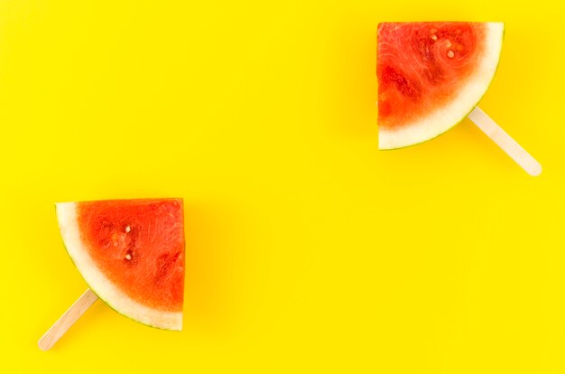 Twee watermeloen slice ijslollys op gele tafel