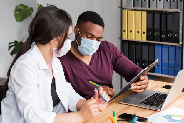 Twee werknemers op kantoor tijdens pandemie met medische maskers