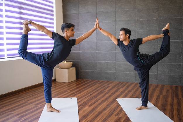 Twee yogi&#39;s die heer van dansers doen poseren in de sportschool