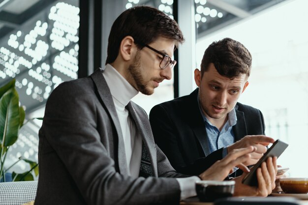 Twee zakenlieden hebben een gesprek met behulp van een smartphone