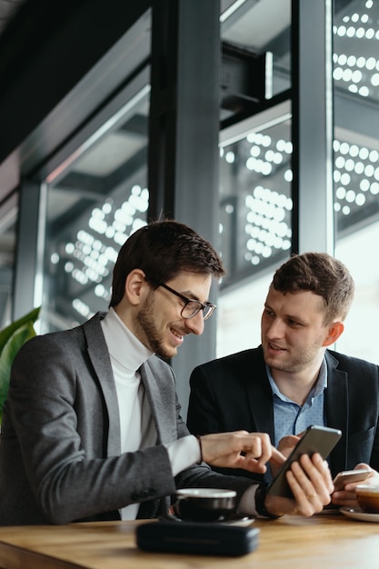 Twee zakenlieden hebben een gesprek met behulp van een smartphone