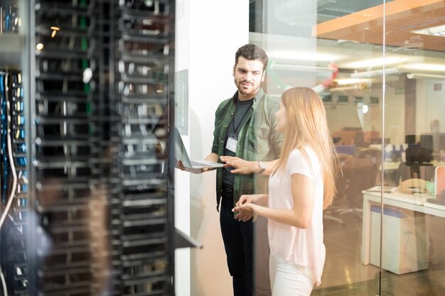 Twee zakenmensen staan in de serverruimte met laptop en bespreken