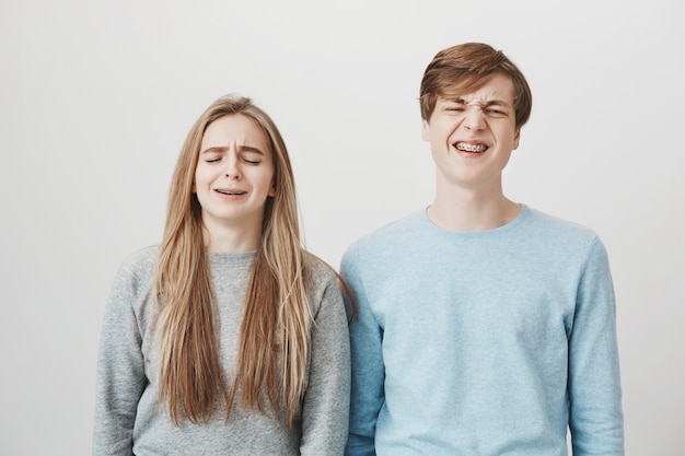 Twee zeurende broers en zussen klagen. Meisje en jongen grimassen