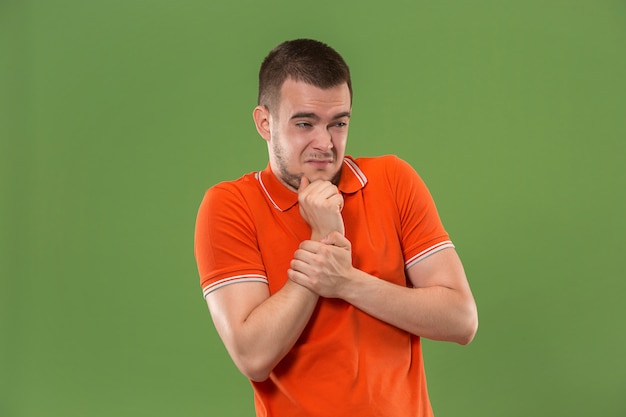 Twijfelachtig nadenkend man met doordachte expressie keuze maken tegen groene muur