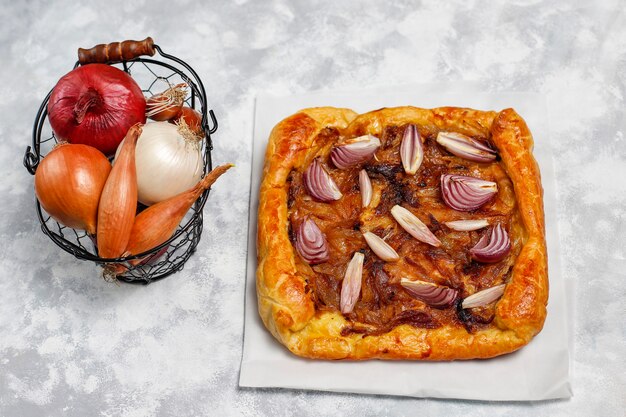 Uientaartgalette in Franse stijl met bladerdeeg en verschillende uiensjalot, rode, witte, gele uien, bovenaanzicht