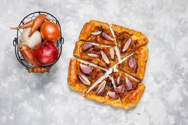 Uientaartgalette in Franse stijl met bladerdeeg en verschillende uiensjalot, rode, witte, gele uien, bovenaanzicht