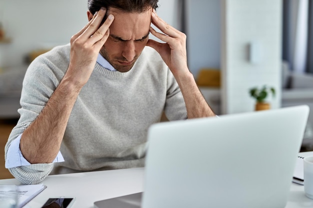 Gratis foto uitgeputte ondernemer met pijn in zijn hoofd na thuis op een computer te hebben gewerkt