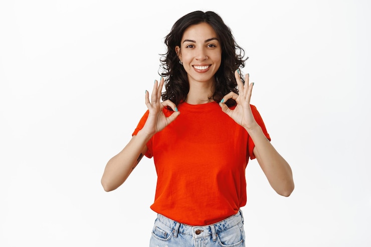 Gratis Foto uitstekend werk, goed gedaan. glimlachende tevreden vrouw maakt compliment, toont oké ok-gebaar en knikt goedkeurend, mee eens of leuk, prijs je keuze, witte achtergrond