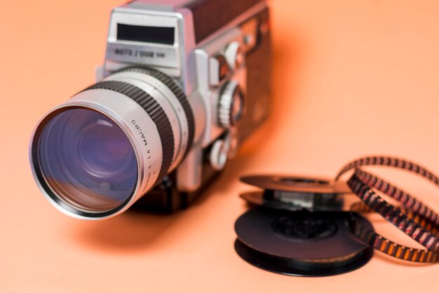 Uitstekende camcordercamera met filmstrook op perzik gekleurde achtergrond