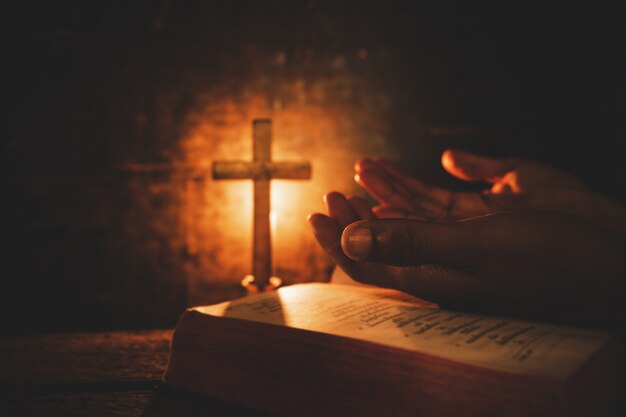 Uitstekende foto van hand met het bidden van de Bijbel