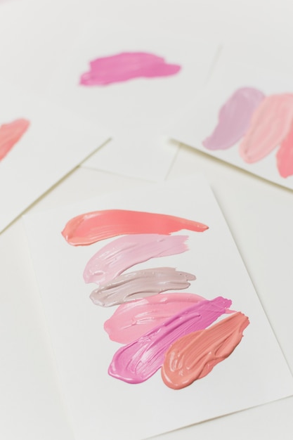 Uitstrijkjes van pastel kleuren lippenstift op vellen papier