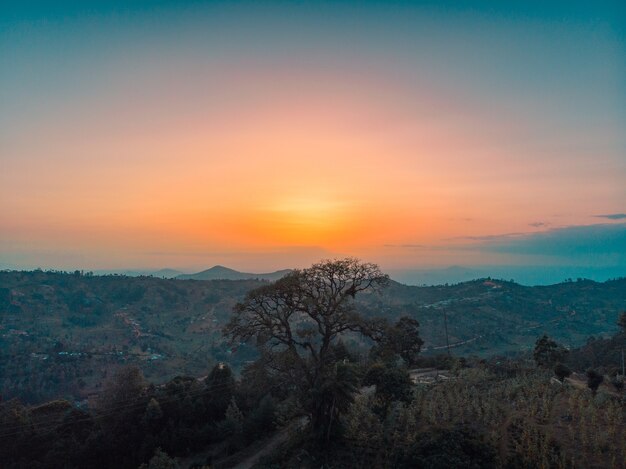 Uitzicht op de met bomen bedekte heuvels met de zonsondergang